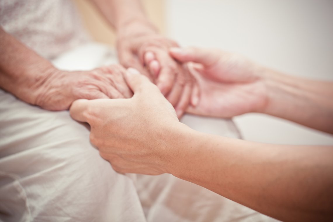 Pflege hält Hände von Patienten